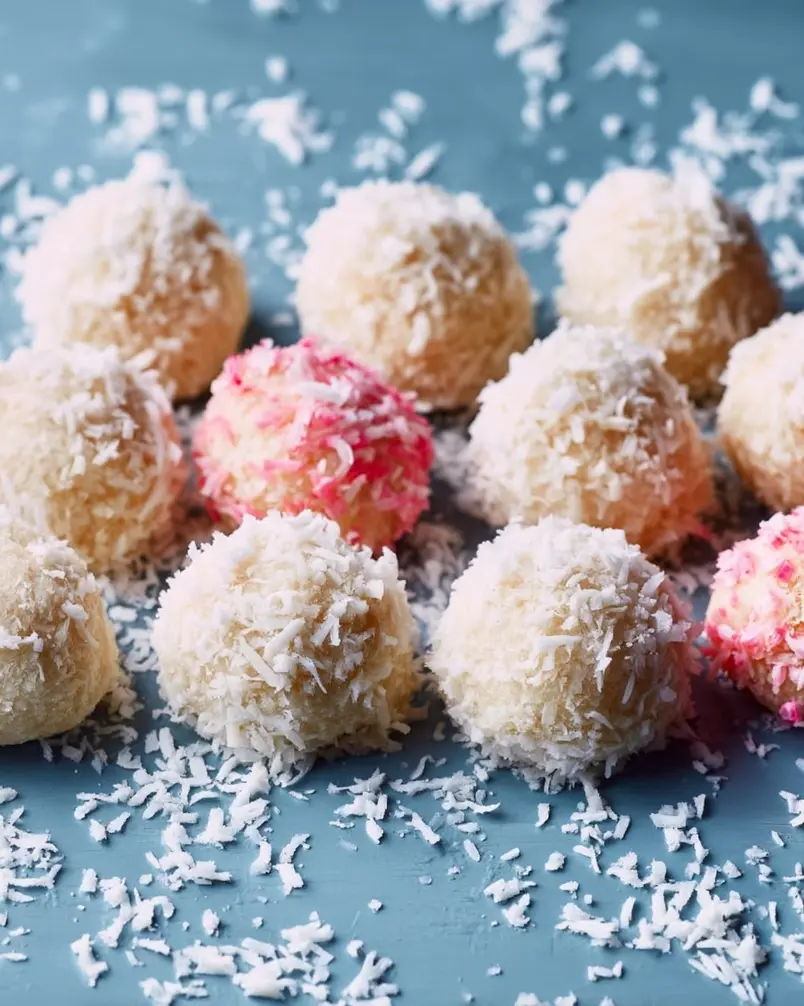 Coconut Cake Snowballs 2 Close-up of ingredients for Coconut Cake Snowballs, including shredded coconut, flour, and sugar, arranged neatly on a kitchen counter.